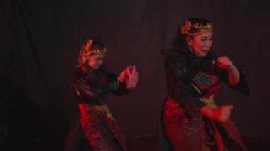 İki dansçı loş ışıkta geleneksel bir dans yapıyorlar. Karmaşık desenli ve başlıklı özenle hazırlanmış kostümler giyiyorlar..