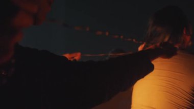 Uzun saçlı, kısmen gölgelerle kaplanmış bir kişinin arkasını gösteren loş bir sahne. Atmosfer kasvetli ve samimi, özel bir an olduğunu gösteriyor..