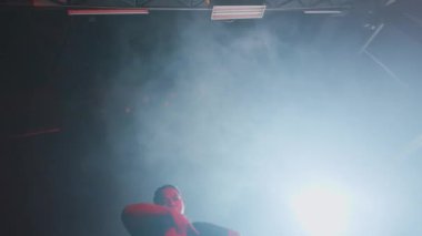 Dramatik ışık ve duman efektleriyle sahnede dans eden bir dansçı, canlı bir atmosfer yaratıyor..