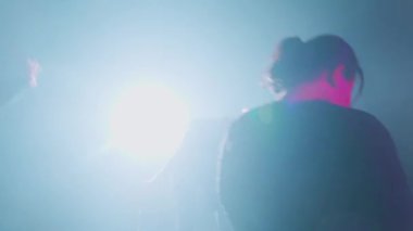 Dramatik bir ışıklandırma düzeninde dans eden, akışkan hareketler ve ifadeler sergileyen bir dansçı. Arka planda, sanatsal atmosferi geliştiren yumuşak mavi bir parıltı var..