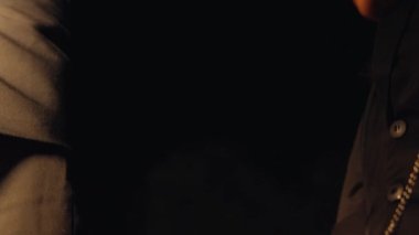 Karanlık bir tünelde, beyaz çizgili siyah bir elbise giyen, sürünerek ilerleyen genç bir çocuk. Yüzü koyu makyajla boyanmış ve yüzünde ciddi bir ifade var..