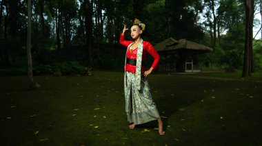 Kırmızı kostüm giyen Endonezyalı bir geleneksel dansçı gün boyunca seyircilerin önünde güçlü bir görsel cazibe yaratıyor.