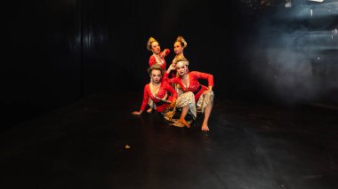 Kırmızı kostüm giyen bir grup geleneksel Cava dansçısı gece sahnede dramatik bir etki yaratıyor.