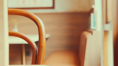 Rahat bir kafe ortamında ahşap bir sandalyenin yakın plan görüntüsü, arka planda bulanık bir tablo ve oturma alanını gösteren yumuşak bir odak.