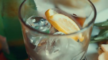 Buzlarla dolu bir bardak ve bir dilim limon, bulanık yiyecek ve içeceklerle dolu..