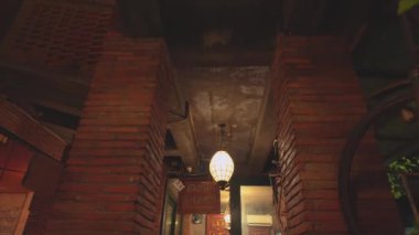 Duvarda asılı bir lamba ve bisiklet de dahil olmak üzere klasik dekorun yer aldığı bir kafe. Tuğla duvarlar ve sıcak aydınlatma davetkar bir atmosfer yaratır..