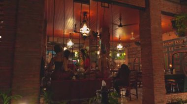 İçinde tuğla duvarlar, ahşap mobilyalar ve dekoratif bitkiler olan samimi bir restoran. Ortam, asılı fenerler ve bir çeşme ile sıcak, hoş bir atmosfer yaratıyor..