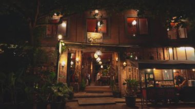 Geceleri sıcacık ışıklar ve dekoratif fenerlerin olduğu güzel aydınlatılmış bir restoran. Girişte bitkiler ve hoş bir atmosfer var. Tuğla mimarisi ve açık hava oturma yerleri sergileniyor..