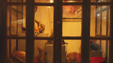 Dekoratif bir eyer ve diğer çeşitli eşyalar da dahil olmak üzere geleneksel eserlerin yer aldığı bir müzede sergilenen bir vitrin. Cam biraz tozlu, sergiye eski bir hava katıyor..