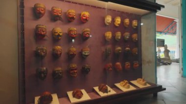 Müze ortamında çeşitli renk ve tasarımların sergilendiği geleneksel maskeler. Maskeler cam bir kutunun üzerine yerleştirilmiş. Karmaşık detaylarını ve kültürel önemlerini vurguluyorlar..