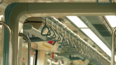 Asılı tırabzanlar ve parlak ışıklandırma gösteren bir metro treni manzarası..