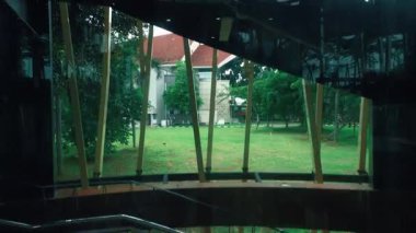 Camdan ve metal elementlerden oluşan modern mimari bir yapı, dışarıda yemyeşil bir bahçesi olan bir merdiven sergiliyor..