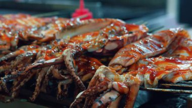 Baharatlı sos serpiştirilmiş, deniz ürünlerinin dokusunu ve detaylarını gösteren yakın plan bir kalamar. Arka plan biraz bulanık, yemeğin canlı renklerini vurguluyor..