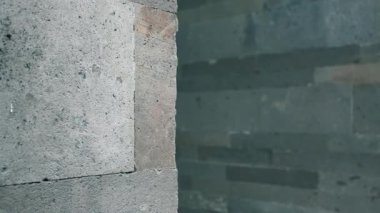 Köşesinde odak noktası olan, pürüzlü yüzeyi ve gri tonlarını gösteren desenli beton bir duvarın yakın çekimi..