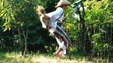 Bereketli yeşil bir çevrede iki kişinin olduğu sakin bir açık hava sahnesi. Bir kişi yerde oturuyor, siyah giyinmiş, diğeri ise arka planda, derin düşüncelere dalmış bir şekilde.. 