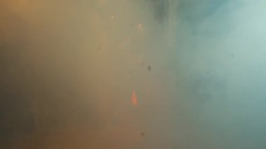 Görüş mesafesini kapatan yoğun dumanlı sisli bir sahne gizem atmosferi yaratıyor. Yumuşak turuncu ışıklar dumandan belli belirsiz görünüyor. Bu da sıcak bir ortam olduğunu gösteriyor..