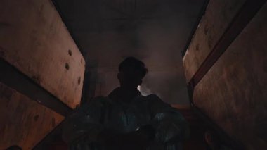 Gölgeler ve dumanla çevrili merdivenlerde oturan siluetli bir figürün loş bir sahnesi. Atmosfer gizemli ve karamsar, aydınlık ve karanlık arasındaki zıtlığa odaklı..