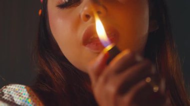 Ateşle tutuşturulmuş çakmağı tutan birinin yakın çekimi. Bireyin neşeli ya da cesur bir ruh hali var gibi görünüyor, aleve ve onların ifadesine odaklanmış. Arkaplan yavaşça bulanık, deneğin özelliklerini geliştiriyor..