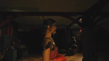 Renkli ışıklarla aydınlatılmış bir sahnede dans eden bir çift. Kadın geleneksel bir elbise giyer, erkek ise takım elbise içinde, canlı bir atmosfer sergiler..