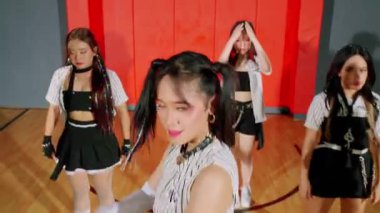 Bir spor salonunda dans gösterisi yapan dört genç kadından oluşan bir grup. Modern ve enerjik bir hava katarak, siyah ve beyaz karışımlı şık kıyafetler giyiyorlar. Arka planda kırmızı ve gri duvarlar var, dinamik atmosferi güçlendiriyor..