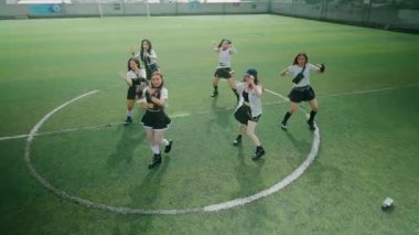 Altı dansçıdan oluşan bir grup çimenli bir alanda koreografili bir gösteri yapıyor. Takım çalışmasına ve enerjiye odaklanarak aynı kıyafetleri giyiyorlar ve dinamik hareketler sergiliyorlar..