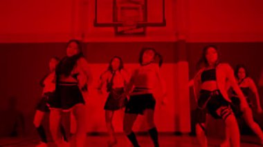 Bir spor salonunda kırmızı ışık efektli altı dansçıdan oluşan bir grup. Modern dans estetiğini yansıtan şık kıyafetler giyip çeşitli dans pozları sergiliyorlar..