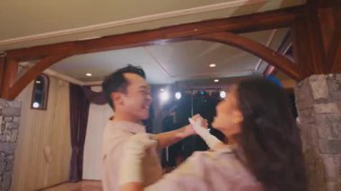 Kapalı bir mekanda canlı bir dans gösterisi. İki dansçı, bir erkek ve bir kadın, neşeyle dans ediyorlar, coşkularını ve yeteneklerini sergiliyorlar. Ayar yumuşak ışıklandırma ve zarif dekor içeriyor, festival atmosferini geliştiriyor..