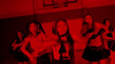 Gösterişli kıyafetler giymiş dört genç kadından oluşan bir grup, loş ışıklı bir spor salonunda kırmızı ışıkla dramatik bir şekilde poz verdiler. Atmosfer yoğun ve enerjiktir. Bir dans ya da performans havası sergiler..