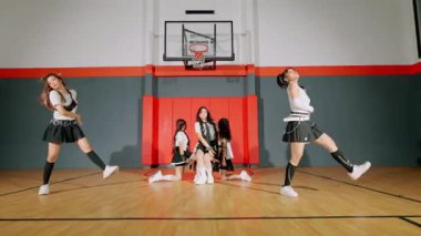 Beş dansçıdan oluşan bir grup bir basketbol salonunda senkronize bir gösteri yapıyor. Etek ve spor ayakkabılarla uyumlu kıyafetler giyiyorlar, dinamik hareketler ve enerji sergiliyorlar..