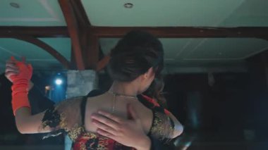 Güzel dekore edilmiş iç mekanda yakından dans eden bir çift zarafet ve samimiyet sergiliyor. Kadın karmaşık dantelli siyah bir elbise giyer, erkek ise şık bir kıyafet giyer. Ortam sıcak ve davetkar.