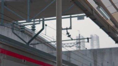 Tren istasyonundaki bir direğin yakın çekim görüntüsü. Kablolar ve yapılar da dahil olmak üzere arka planda bulanık elementler var. Olay yeri bir şehir ulaşımı hissi veriyor..