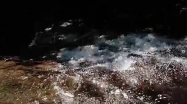 Işıl ışıl yansımalar ve kabarcıklarla akan suyun yakın çekim görüntüsü sakin ve sakin bir atmosfer yaratıyor..