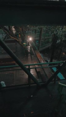 Tahta kaldırımları ve yeşil korkulukları olan sakin bir orman manzarası. Yumuşak ışık yolu aydınlatır, sakin bir atmosfer yaratır. Sahne, doğal güzelliği artıran yemyeşil ağaçlarla çevrili..