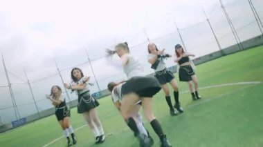 Spor sahasında dinamik bir dans gösterisi, şık kıyafetler içinde birden fazla dansçı. Sahne, ön plandaki bir dansçıya odaklanarak enerji ve hareketi yakalıyor..