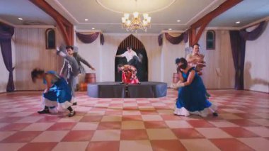 Süslü bir salonda altı dansçının sahne aldığı canlı bir dans gösterisi. Dansçılar renkli kostümler giyiyorlar. Geleneksel kıyafetlerle, canlı bir atmosfer sergiliyorlar..