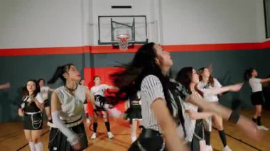 Çizgili elbiseli bir grup sanatçının olduğu dinamik bir dans sahnesi. Bir dansçı, dalgalı saçları ve neşeli bir ifadeyle odaklanırken, diğerleri arkada enerjik bir şekilde hareket ediyor..