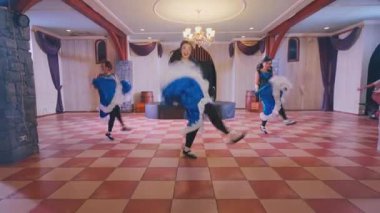 Renkli kostümlü dört dansçının yer aldığı canlı bir dans gösterisi. Geniş, zarif dekore edilmiş bir salonda geleneksel dans figürleri sergiliyorlar..