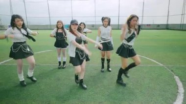 Spor sahasında beş genç bayandan oluşan dinamik bir dans gösterisi. Siyah beyaz çizgili şık kıyafetler giyiyorlar, enerjik hareketler sergiliyorlar ve senkronize koreografi yapıyorlar..