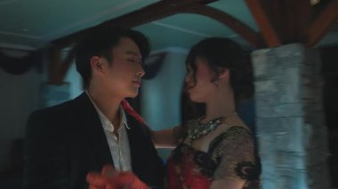 Renkli elbiseli bir kadın zarif bir şekilde boş, zarif bir salonda dans eder. Ortam yumuşak bir aydınlatma ve klasik bir avize içeriyor. Romantik bir atmosfer yaratıyor..