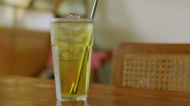 Tahta bir masaya konmuş taze, buzlu, yeşil bir çay. İçecekler buz küpleriyle berrak, canlı yeşil renkler sergiliyorlar..