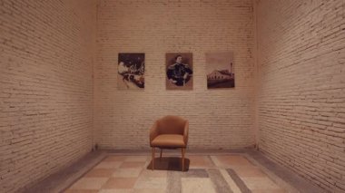 Ortasında tek bir sandalye bulunan minimalist bir galeri. Beyaz tuğladan duvara asılmış üç çerçeveli fotoğraf çeşitli konuları sergiliyor. Yerin desenli bir tasarımı var. Huzurlu ortama doku ekliyor..