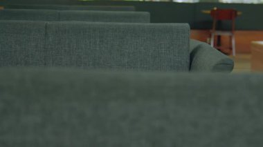 Gri döşemeli koltukların yakın plan görüntüsü modern iç dekorda, bulanık bir arka plan ile ahşap bir masa ve sandalyeler sergileniyor..