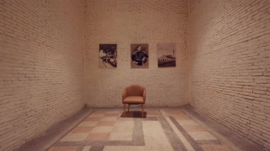 Ortasında tek bir sandalye bulunan minimalist bir galeri. Duvarlar açık renkli tuğlalardan yapılmış ve duvarda asılı üç eski fotoğraf modern ortama biraz tarih katıyor. Zeminin geometrik deseni var.