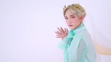 Kısa, açık renk saçlı, zarif bir şekilde tasarlanmış, nane yeşili fiyonklu bir elbise giyen biri. Narin bir başlıkları ve hafif bir arkaplanda zarif bir şekilde poz veren yumuşak bir ifadeleri var..