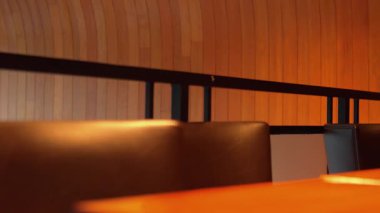 İçinde ahşap duvarlar ve koyu deri sandalyeler olan bir restoranın içi. Sıcak ışık davetkar bir atmosfer yaratıyor, yemek için mükemmel..