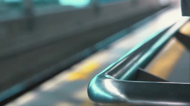 Bir tren istasyonundaki metalik korkulukların yakın plan görüntüsü. Arka planda bulanık izler var. Odak noktası parmaklıkların pürüzsüz, parlak yüzeyi, yansıtan ışık..