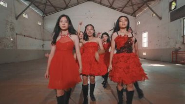Bir grup kırmızı elbiseli dansçı endüstriyel alanda koreografi gösterisi yapıyorlar. Dansçılar dinamik pozlar sergiliyor, enerji ve senkronizasyon sergiliyorlar..