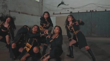 Bir grup dansçı geniş bir iç mekanda koreografi gösterisi yapıyorlar. Süslü püslü kıyafetler giyerler ve orta hareket sırasında yakalanırlar. Enerji ve senkronizasyon gösterirler..