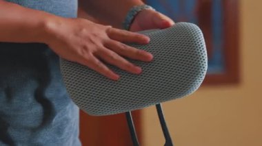 Siyah ve gri bir cihaz tutan bir kişi, muhtemelen bir başlık ya da ergonomik aksesuar, ayarlanabilir destek mekanizmasını sergiliyor. Arkaplan hafifçe bulanık, nesneyi vurguluyor.