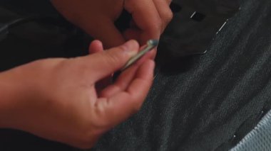 Kilit anahtarı ile metal bir bileşeni bir araya getirerek sürgüyü sıkmaya odaklanan yakın plan bir el. Arkaplan bulanık, inşaatın eylemlerini vurguluyor.